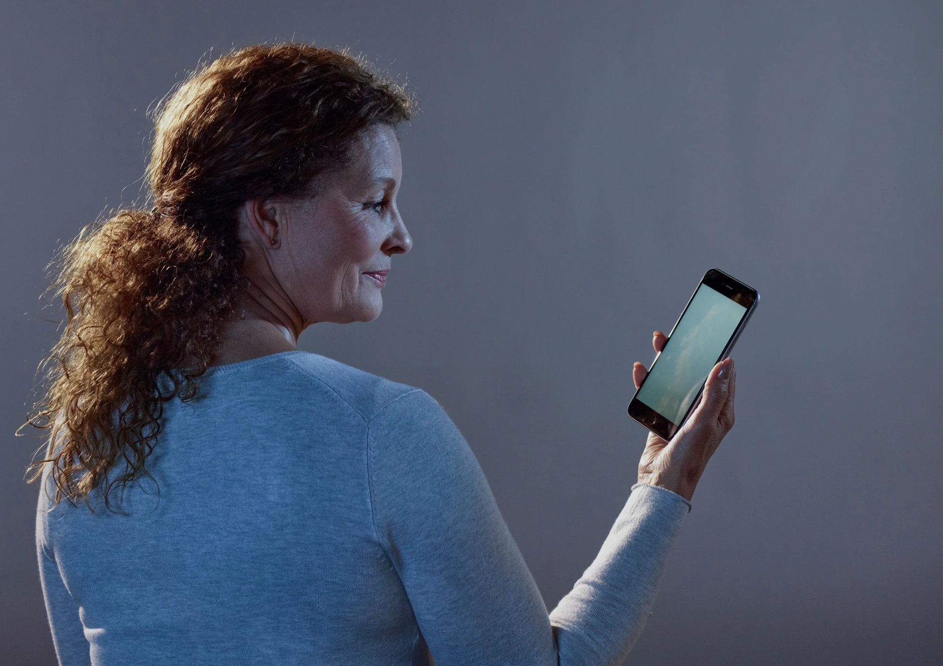 Woman holding phone, against a backdrop of studio
